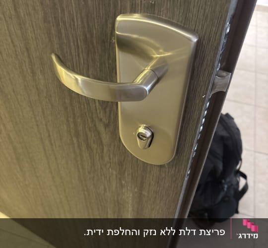 ידית דלת מתכתית על דלת עץ